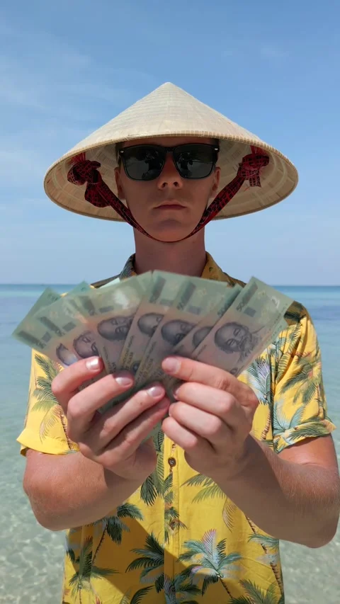Man in Vietnamese hat counting Vietnamese Dong bills on exotic beach in Vietnam Stock Footage 306516211