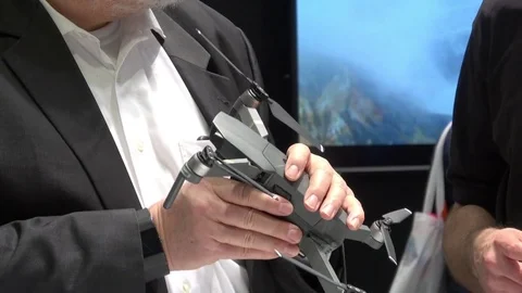 Man viewing and holding in hand Mavic Pro drone by DJI company on exhibition Stock Footage 74110843