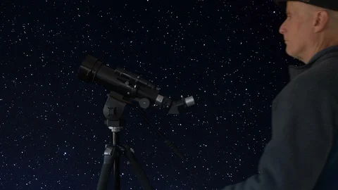 A man viewing stars through a telescope Stock Footage 99003298