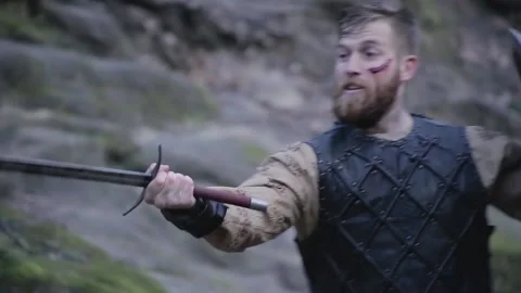 Man in Viking clothes with axes attacks another Viking with sword and shield Stock Footage 132992327