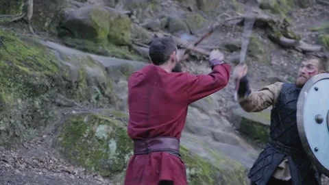 Man in Viking clothes with axes attacks another Viking with sword and shield Stock Footage 132992548