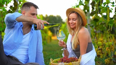 A man in a vineyard pours white wine into a woman's glass Stock Footage 296045715