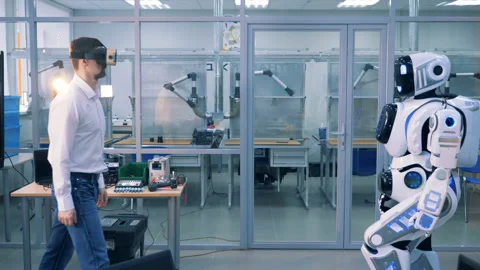 A man in virtual glasses and a robot are giving each other high-five Stock Footage 90062184