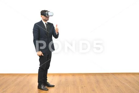The man with a virtual reality glasses thumbs up on the white wall background Stock Photos