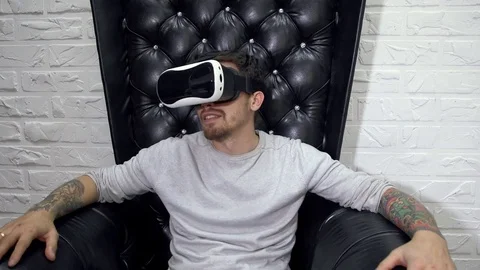 Man in virtual reality goggles sits on the leather armchair. Stock Footage 70797808