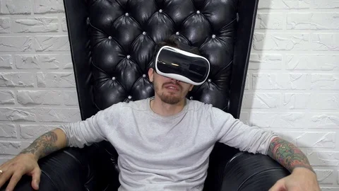Man in virtual reality goggles sits on the leather armchair. Stock Footage 70797851
