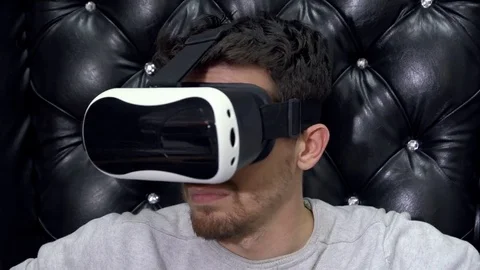 Man in virtual reality goggles sits on the leather armchair. Stock Footage 70797863