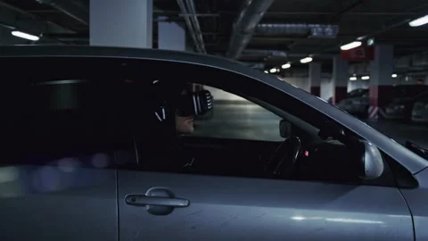 Man in virtual reality headset parking car in underground garage 库存影片 332537497