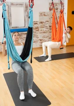 Man visitor performs exercises in hanging position on Pilates slings hammock Stock Photos