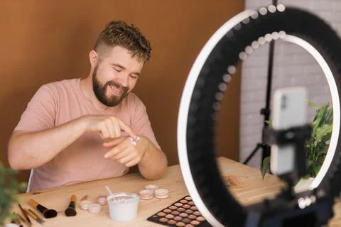 Man vlogging about make up and beauty products. Male shooting a makeup tutorial 库存照片