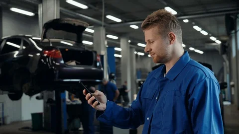 Man voice recognition with smart phone in car mechanic workshop service factory Stock Footage 95260702