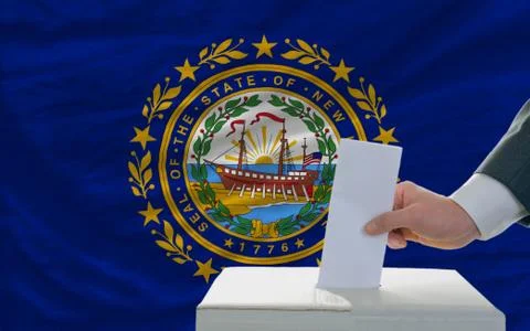 Man voting on elections in front of flag us state flag of new hampshire Stock Photos