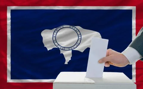 Man voting on elections in front of flag us state flag of wyoming Stock Photos