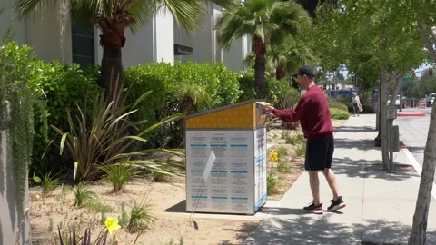 A man voting in a local CA election by dropping his ballot off in a drop box Stock Footage 196848926