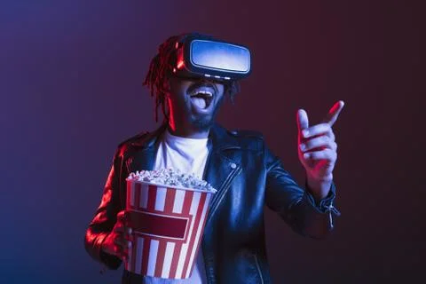 Man with VR glasses and popcorn watches a 3D film Stock Photos