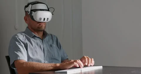 Man in VR goggles typing keyboard, virtual reality monitor at home. Stock Footage 257724506
