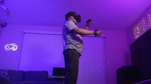 Man in VR headset actively moving while playing virtual reality at home Stock Footage 334089549