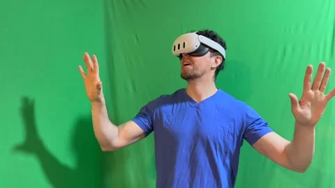 Man in VR headset discovered metaverse near green wall then takes off helmet Stock Footage 282531487