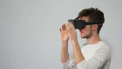 Man with VR headset enters a virtual reality world and interacts with the e.. Stock Footage 71468928