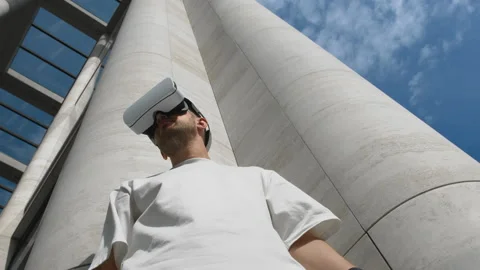Man in VR headset exploring virtual world standing near modern urban building Stock Footage 158639284