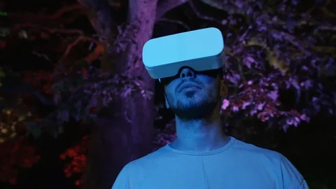 Man in VR headset gadget immersed into virtual reality and looks around. Stock Footage 107126954