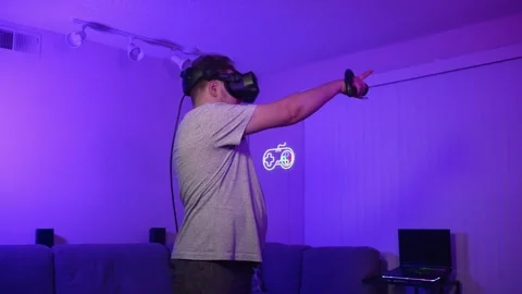 Man in VR headset pointing forward with controller interacting with game Stock Footage 334089833