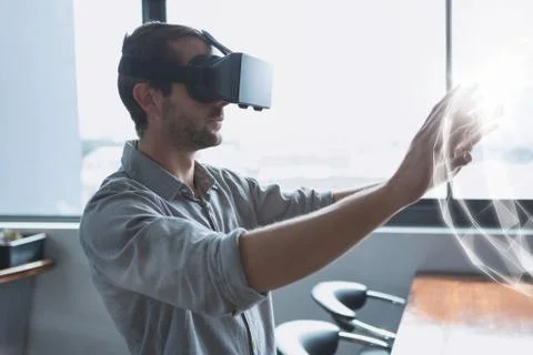 Man in VR headset touching a 3D sphere interface Fotos Stock