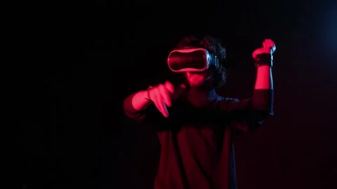 Man with VR helmet on his head playing in red-blue lights, online party. Stock Footage 151333489