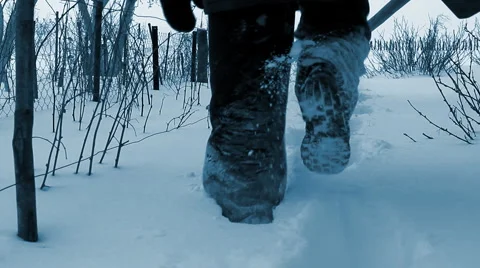 Man wades knee-deep through snow with shovel in countryside Stock Footage 1160206