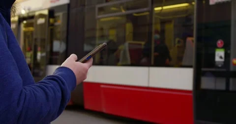 Man waiting tram, engrossed smartphone. Scene depicts urban life, with focus Stock Footage 257592077