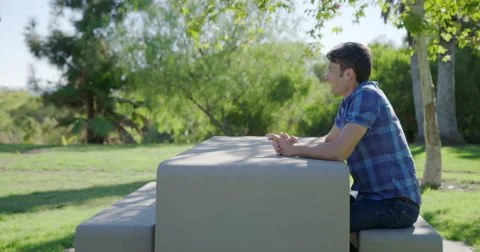 Man waits at concrete bench table in a park in Los Angeles 4K Stock Footage 68409714