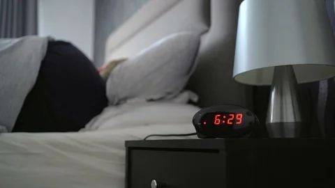 Man wakes for work when alarm sounds and hits snooze button blindly with Stock Footage 129950905