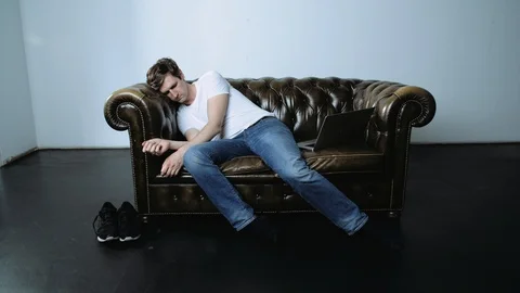 Man Waking Up on Leather Sofa and Using Laptop Stock Footage 120133840