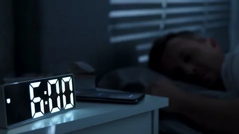 Man waking up, turning off alarm clock on digital clock and smartphone. Sle.. Stock Footage 291983919