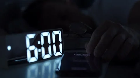 Man waking up, turning off alarm clock on digital clock and smartphone. Sle.. 動画素材 291985893