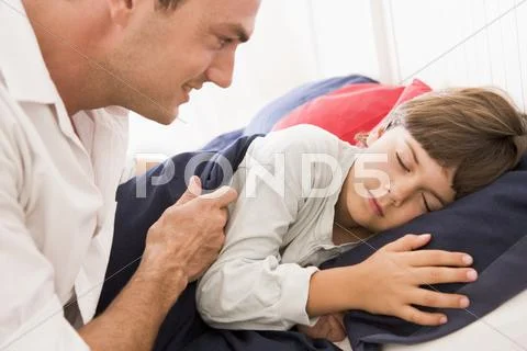 Man waking young boy in bed smiling Stock Photos