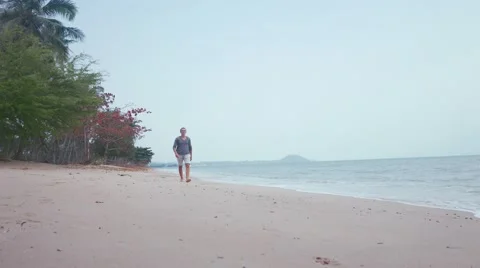 Man walk on the background of beautiful beach with white sand and cloudy sky Stock Footage 61511084