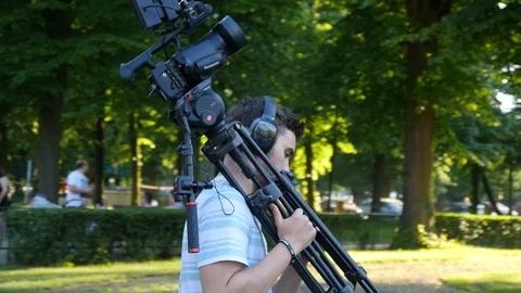 Man walk With Camera and Tripod For Tv Channel, recording Video on a Festival Stock Footage 109085673