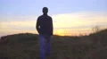 The man walk on the mountain against the background of sunset. Real time capture 4k or 4k+ Resolution