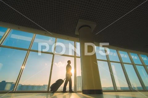The man walk with a suitcase near panoramic windows Stock Photos