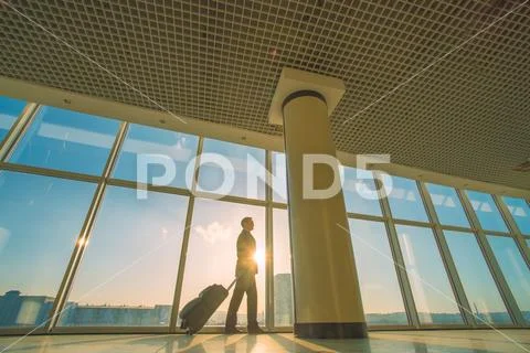 The man walk with a suitcase near panoramic windows Stock Photos