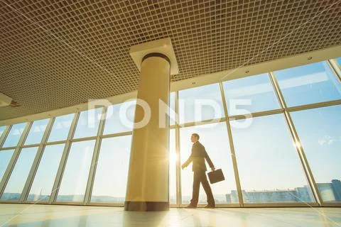 The man walk with a suitcase in the office hall Stock Photos
