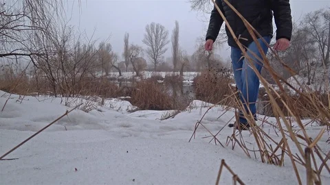 Man walk through the snow in a park near the river. Stock Footage 102045899