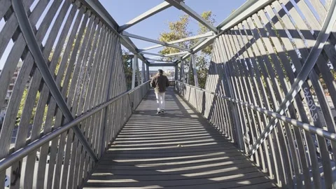 Man walking across an elevated bridge 4k Stock Footage 323951847