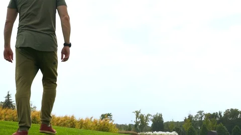Man walking across short grass in a park Stock Footage 95288635
