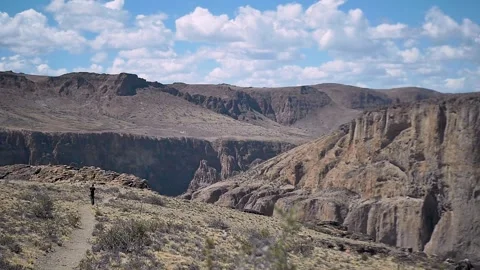 Man walking alone on desert track by the canyon Stock Footage 255895989