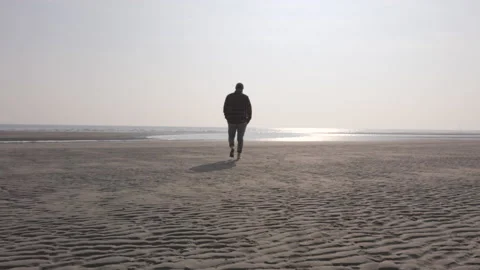 Man walking alone on a empty beach Stock Footage 233985502