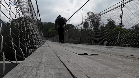 A man walking alone on suspension bridge Stock Footage 247163760