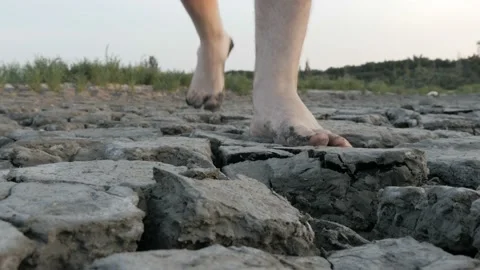 Man walking alone through dry deserted land with cracked soil Stock Footage 94817041