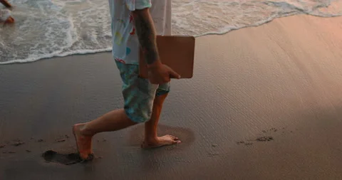 A man is walking along the beach with a computer tablet in his hands Stock Footage 105734972
